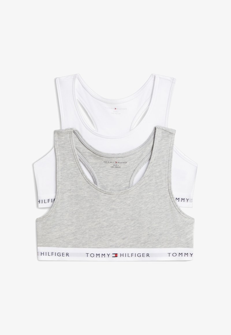 Δύο αθλητικά σουτιέν Tommy Hilfiger με racerback, ένα ανοιχτό γκρι και ένα λευκό, στοιβαγμένα με ελαστικές ταινίες στο κάτω μέρος.