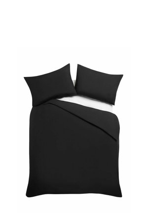 Doppelbett mit zwei schwarzen Kissen und schwarzem Bettbezug auf weißem Laken, von oben vor weißem Hintergrund.