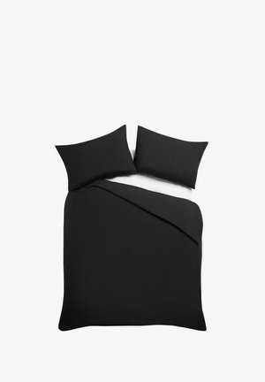 Doppelbett mit zwei schwarzen Kissen und schwarzem Bettbezug auf weißem Laken, von oben vor weißem Hintergrund.