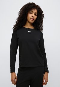 Mustast pehmest kangast valmistatud pika varrukaga särk, millel on ümarsärk ja väike valge "BOSS" logo rinnal. Lihtne, sirge lõikega disain.