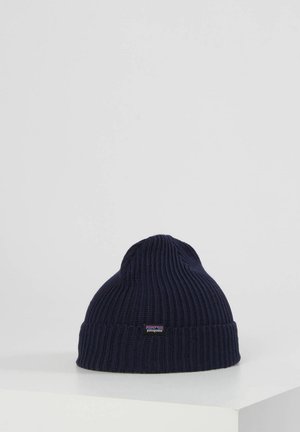 Gorro de punto en color marino con textura acanalada y borde doblado. Presenta una pequeña etiqueta con el logo en el lado. Hecho de material suave y elástico.