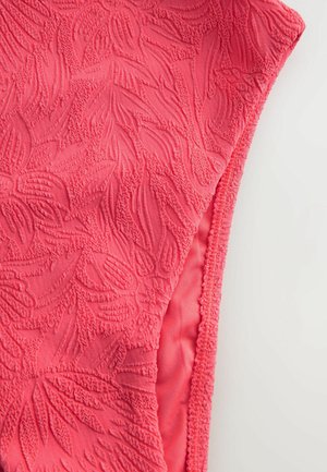 Różowa tkanina z podniesionymi wzorami kwiatowymi i fakturowanymi detalami, z gładkimi krawędziami i miękką, lekką teksturą.