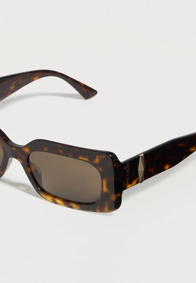 Ορθογώνια γυαλιά ηλίου με σχέδιο χελώνας, σκούρους φακούς και χρυσές γεωμετρικές λεπτομέρειες στα μπράτσα.