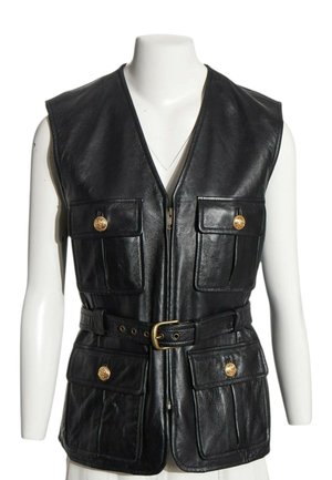 Veste sans manches en cuir noir avec fermeture éclair sur le devant, quatre poches à rabat avec boutons dorés, et une ceinture avec boucle dorée à la taille sur un mannequin blanc.
