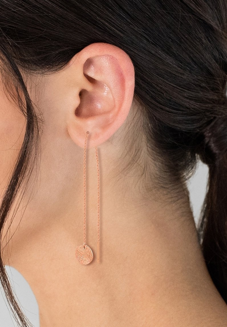 Gli orecchini in oro rosa presentano una lunga catena con un ciondolo circolare texturizzato, accentuato da un semplice design a goccia dritta.