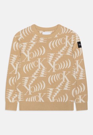 Jersey de punto beige con logo blanco "CK" de Calvin Klein y patrones geométricos por toda la prenda, con puños y dobladillo de canalé y una etiqueta con logo negro en la manga.