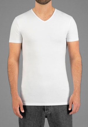 Witte T-shirt met korte mouwen en V-hals, gemaakt van gladde stof, met een fitted ontwerp, naadloze textuur en een strakke zoom. Gekozen in combinatie met donkere spijkerbroeken.
