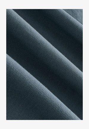 Tejido textil en gris oscuro, con una textura suave y sutiles variaciones en el tono. Los pliegues de la tela crean líneas suaves y fluidas.