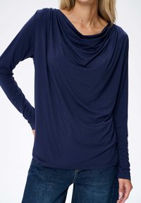 Marineblaue Langarmbluse mit drapiertem Ausschnitt und weichem, glattem Stoff. Hat enganliegende Ärmel und eine fließende Silhouette.