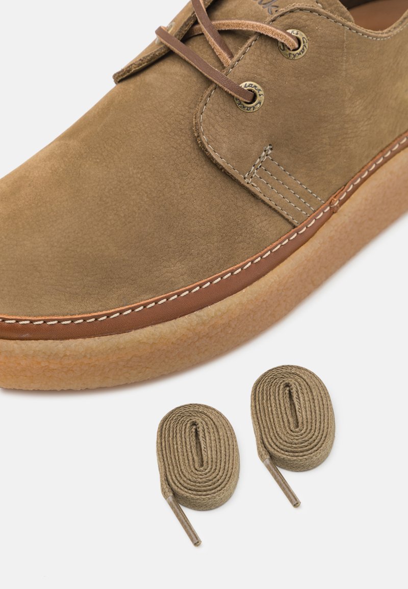 Scarpa in suede marrone con accenti in pelle brown a contrasto, suola in gomma e cuciture leggere. Sono inclusi due lacci abbinati in brown.