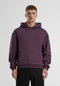 Lila Baumwollkapuzenpullover mit einer Fronttasche, gerippten Bündchen und Saum. Verfügt über eine Kordelzugkapuze und einen lockeren Schnitt.