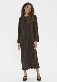Vestido maxi plisado marrón con mangas largas y escote redondo, con una tela texturizada y un dobladillo con un sutil volado.