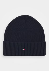 Marineblaue Strickmütze mit geripptem Muster, ausgestattet mit einem kleinen Logostreifen in Rot, Weiß und Blau am umgeschlagenen Bund.