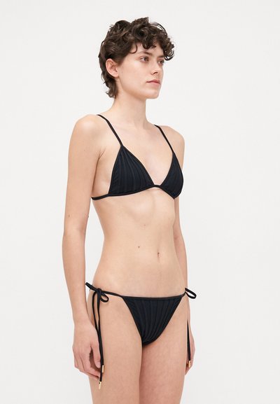 Melnā bikini komplekts ar ribotu tekstūru, trīsstūrveida topu ar plānām siksnām un zemu vidukli ar regulējamiem sānciem un zelta akcentiem.
