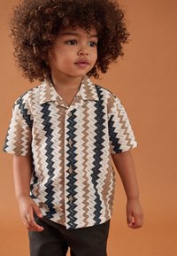 Kurzärmeliges Hemd mit Zickzackmuster in Beige, Braun und Marineblau. Die Vorderseite ist mit Holzknöpfen verziert, hat einen spitzen Kragen und eine weiche Textur.