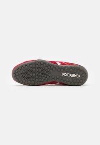 Sole di scarpa atletica rossa con gomma grigia testurizzata, caratterizzata da motivi di trazione circolari e dal nome del marchio "GEOX" impresso.