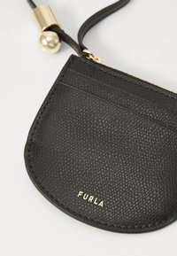 Black leather pouch with a textured finish, featuring gold-tone hardware and a logo. Includes slots for cards and a zip closure.