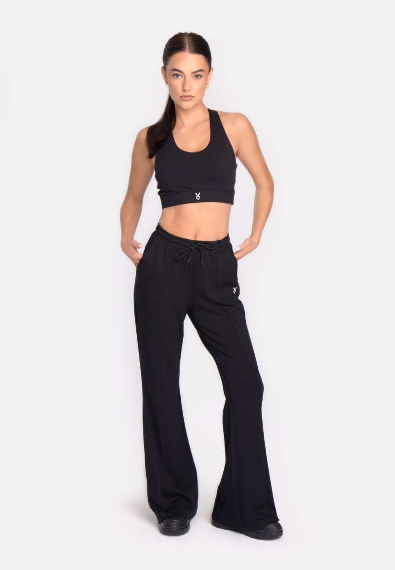 Top scurt negru și pantaloni cu talie înaltă dintr-un material moale, având un cordon la talie și un logo minimalist pe față.