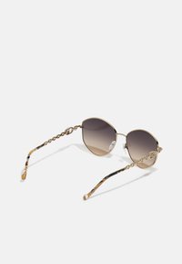 Round sunglasses with gradient brown lenses, gold-tone frame, and unique chain-accented arms featuring a tortoiseshell pattern.