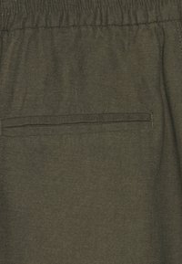 Olivgrüne Stoffshorts mit strukturierter Oberfläche, elastischem Bund und einer einzelnen Gesäßtasche mit gesticktem Detail.