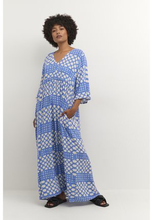 Blue maxi dress with a V-neck and short, flared sleeves; features a cream circular pattern and pockets on the sides. Paired with black sandals.