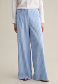 Pantalones de pierna ancha de color azul claro en una tela ligera, con rayas verticales blancas y una cinturilla plana. La textura parece suave.