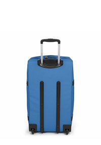 Valigia blu con una superficie in tessuto liscio, manico retrattile e quattro ruote nere. Presenta dettagli in metallo nero e una chiusura con zip.