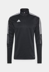 Czarny pulower na zamek ćwierć z gładkiego materiału, z białym logo Adidas i trzema białymi paskami wzdłuż każdego rękawa. Długie rękawy z dopasowanymi mankietami.