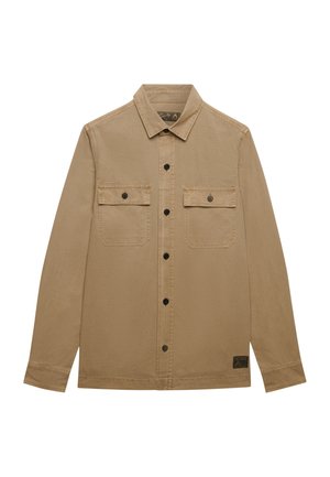 Beige heren overhemd met lange mouwen, knoopsluiting, kraag, twee borstzakken met knoopklep aan de voorkant, en een klein zwart label vlak bij de onderzoom.