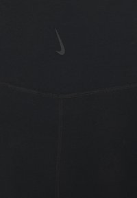 Musta venyvää urheilukangasta, jossa on huomaamaton Nike-logo. Sisältää kontrastiväriset saumaompeleet, joka korostaa muotoilua.