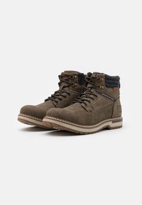 Bottines en daim marron avec un col en tissu gris, œillets en métal et semelle en caoutchouc. Détails cousus et accent logo sur le côté.