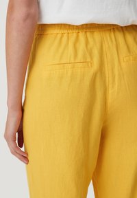 Geel linnen broek met een elastische tailleband en twee achterzakken, met een zachte textuur en een comfortabele pasvorm.