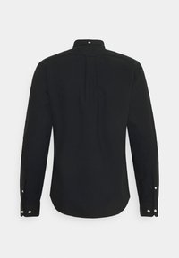 Chemise noire à manches longues boutonnée, vue de dos, avec poignets boutonnés et un petit pli sous le col.