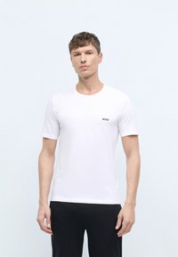 White cotton t-shirt with short sleeves, round neckline, and a small green "BOSS" logo on the left chest. Smooth texture, fitted design.