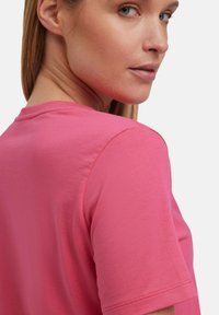 Korte mouwen, ronde hals t-shirt in een levendige roze kleur. Vloeiende katoenmateriaal met een ontspannen pasvorm en schone stiksels op de mouwen.