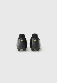 Zwarte voetbalschoenen met een stijlvolle uitstraling, met ribbelstructuur en groene accenten, gezien vanuit de achterkant tegen een witte achtergrond.