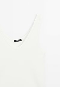 Witte geribbelde tanktop met ronde halslijn en brede schouderbanden, gelabeld "Massimo Dutti," plat gelegd op een witte achtergrond.