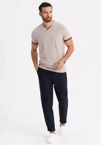 Lys grå V-hals T-shirt med maroon-detaljer, parret med mørk marineblå bukser og hvide slip-on sko. Enkel og ren design.