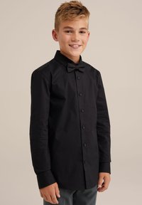 Chemise noire à manches longues avec un devant à boutons et un nœud papillon assorti. Le tissu est lisse avec une coupe ajustée et des poignets à boutons.