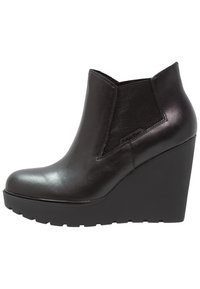 Botín de cuña de cuero negro con acabado liso, puntera redondeada, paneles elásticos en los costados y una suela gruesa y texturizada.