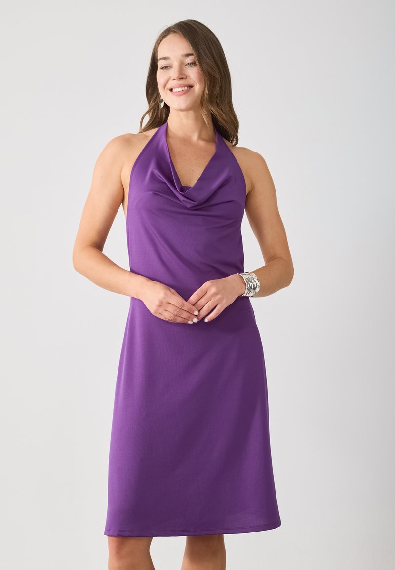 Violetti halterneck-mekko, jossa on kankaallinen kaula-aukko, polviin ulottuva leikkaus ja sileä pinta. Mekossa on istuva yläosa ja levenevä hameosa. Yksinkertainen, elegantti muotoilu.