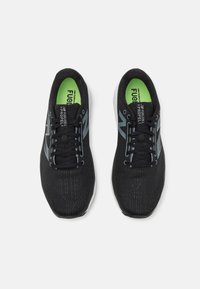 Schwarze Sportschuhe mit einer strukturierten Oberfläche, kontrastierenden grauen Akzenten und grünen Einlegesohlen. Verfügt über traditionelle Schnürsenkel und eine gepolsterte Sohle.