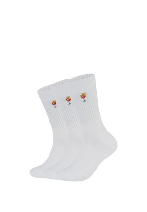 Trois chaussettes blanches côtelées montantes avec des verres à cocktail brodés, ornés de tranches d'orange et de pailles près du haut.