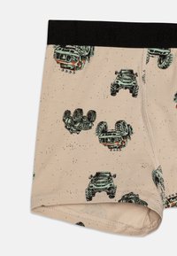 Boxer en coton beige avec un motif de camions monstres verts à l'envers et à l'endroit. Ceinture élastique noire.
