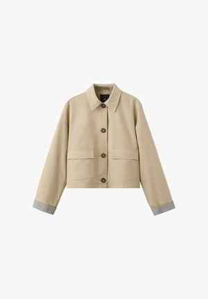 Chaqueta corta beige hecha de mezcla de algodón, con cierre frontal de botones, dos grandes bolsillos y puños de canalé grises.