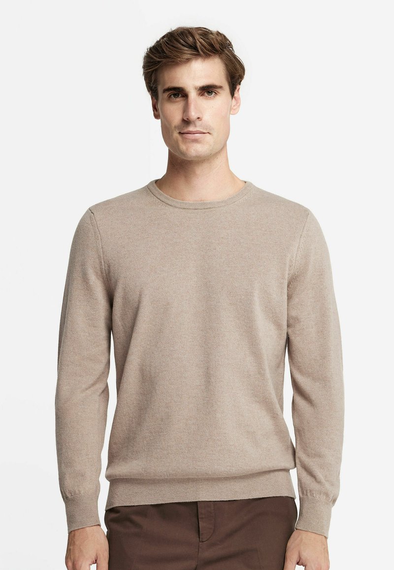 Tan långärmad tröja i mjukt stickat material med rundad halsringning och ribbade ärmslut och nederkant. Slät textur, minimal detaljering, figurnära design.