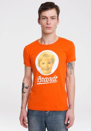 Orange cotton t-shirt featuring a large round graphic of a smiling child’s face with the name "Brandt" in white lettering below.