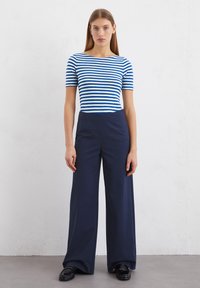 Blue and white striped short-sleeve top paired with navy wide-leg trousers. The outfit features a boat neckline and smooth fabric texture.