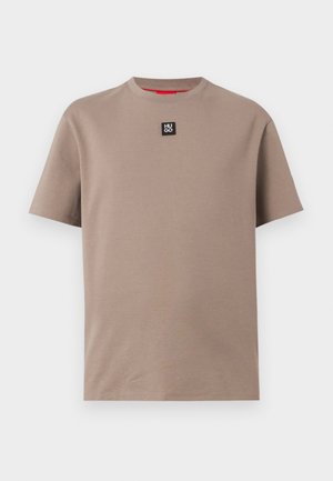 Bézs rövid ujjú környakú póló, kicsi fekete "HUGO" logó folttal, amely a gallér alatt középen helyezkedik el.