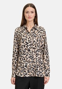 Leopardenmuster-Hemd mit Knöpfen aus weichem Stoff, mit langen Ärmeln, spitzem Kragen und relaxed Fit. Schwarz- und Brauntöne dominieren das Muster.